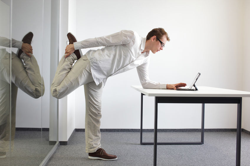 Man stretching leg while using laptop