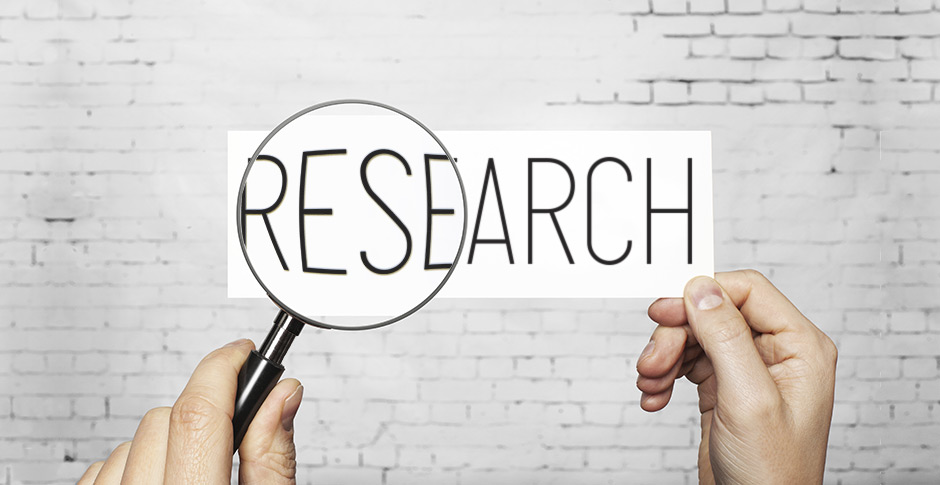 Hands holding magnifying glass over research